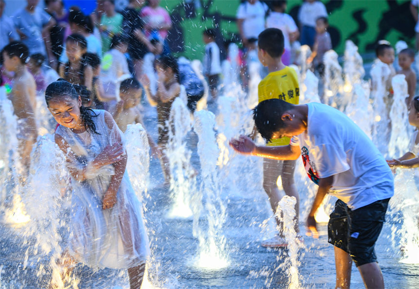 重慶連晴高溫，小朋友在南濱路噴泉下戲水玩耍享受清涼。郭旭攝