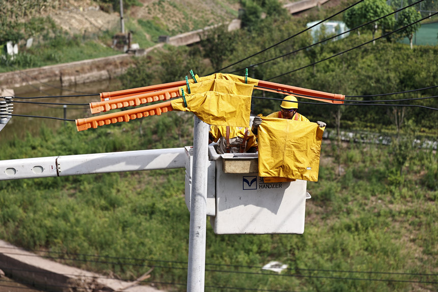 電力公司工作人員在電線上鋪上絕緣毯。國網重慶市電力公司供圖