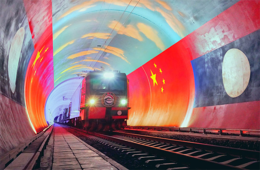 在中國和老撾兩國國旗映襯下，衛生列車即將在中老鐵路“友誼隧道”內跨越中老兩國邊境。凱喬攝
