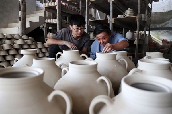 羅達川（左）跟劉沛良學檢查陶坯的質量。黔江區委宣傳部供圖