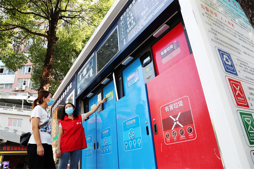 在生活垃圾分類服務驛站，管理員（右）在給市民講解使用垃圾智能分類的方法。楊敏攝