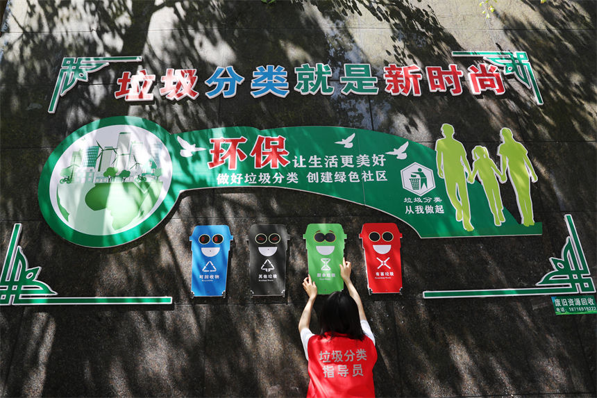 在當地黔龍陽關國際小區垃圾分類集中收集亭，垃圾分類宣傳員在整理垃圾分類廣告牌。楊敏攝