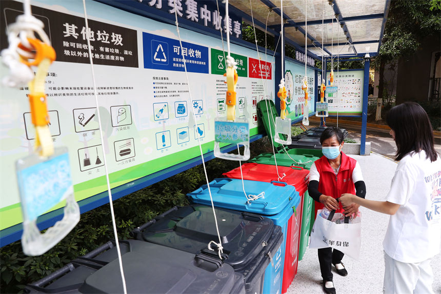 在當地黔龍陽關國際小區垃圾分類集中收集亭，垃圾分揀員（左）指導市民垃圾分類。楊敏攝