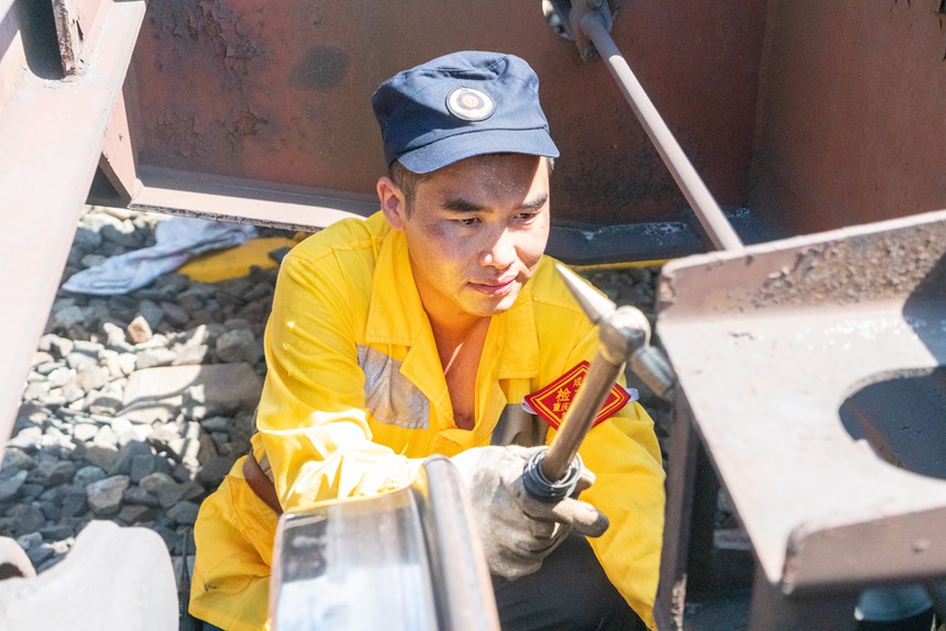 8月9日，重慶西車輛段貨車檢車員正在檢查中歐班列底部吊架技術狀態。劉彪攝
