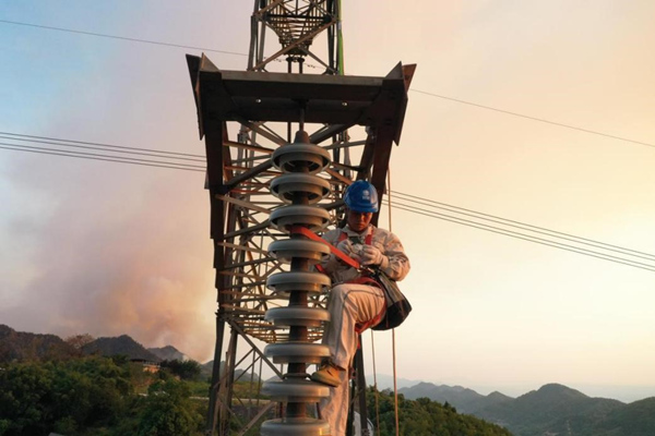 電力工人登塔開展搶修作業。李濤攝
