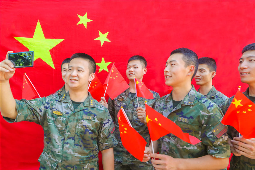 武警官兵與國旗合影，分享國慶喜悅。李東攝