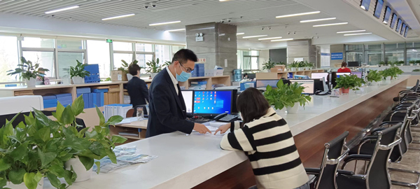 云陽縣行政審批大廳工作人員向建筑公司介紹分階段辦理施工許可證。云陽縣住建委供圖