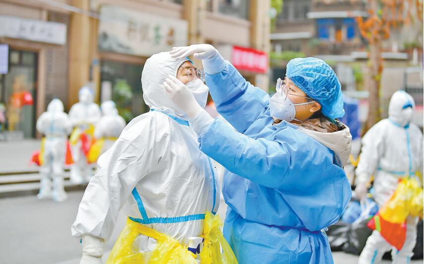 11月14日，九龍坡區楊家坪街道興勝路社區，志愿者陳曉宇（右）正在幫助醫護人員穿防護服。記者 鄭宇 通訊員 孫小剛 攝/視覺重慶