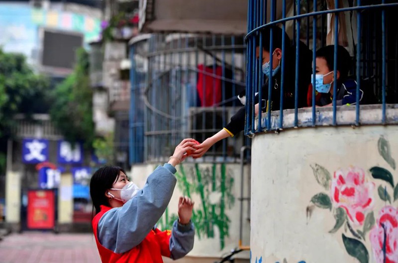 11月18日，南岸區長生橋鎮桃花橋社區移民小區，一位小朋友為正在小區巡查的大學生志愿者李江玲送上了一個蘋果。此次共有35名來自重慶多所高校的志愿者參加到長生橋鎮的疫情防控工作中。王雄 攝