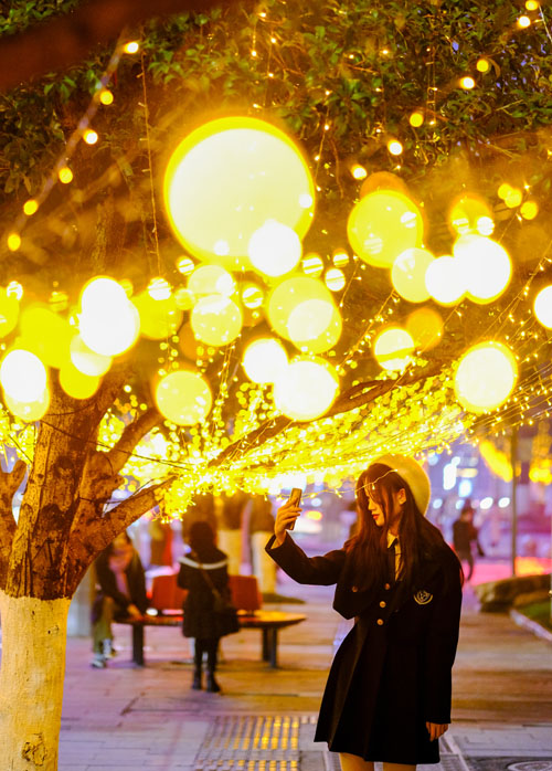 市民在流光溢彩的彩燈前留影。郭旭攝