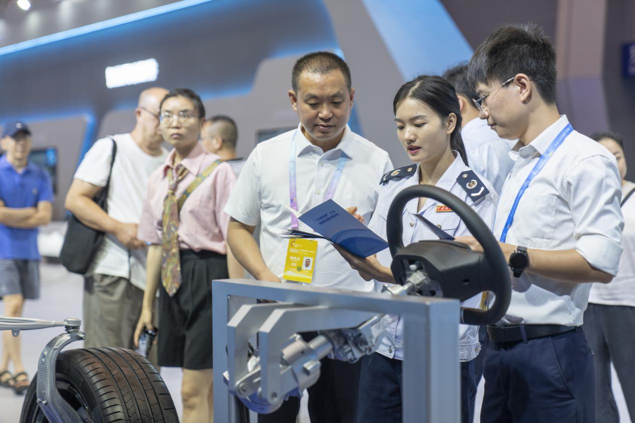 智博會現場，在重慶龍潤汽車轉向器有限公司展區，璧山區稅務人員正宣傳研發費用加計扣除等稅收優惠政策。郭睿攝