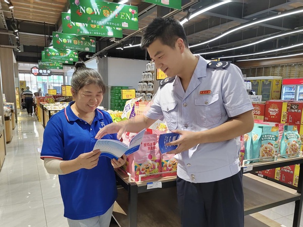 巫山縣稅務人員來到當地超市，送上批發零售業稅收優惠政策宣傳冊。羅超斌攝