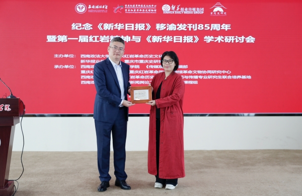 西南政法大學新聞傳播學院副院長蔡斐（左）向新華報業傳媒集團《傳媒觀察》雜志贈送1952年《新華日報》訂報收據。西南政法大學供圖
