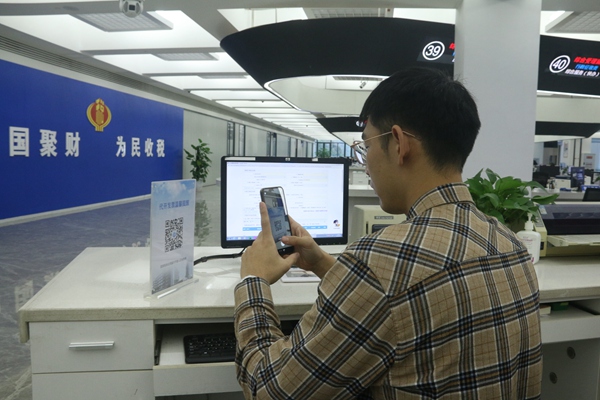 在璧山區辦稅服務廳自助辦稅區，納稅人正在掃描“代開發票稅率表”二維碼。梅渝攝