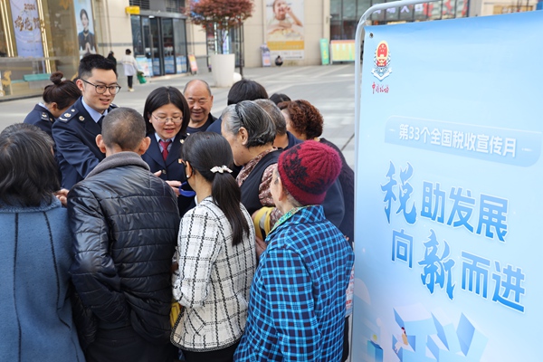 近日，在城口縣名豪廣場，稅務人員為群眾發放社保宣傳手冊。重慶市稅務局供圖
