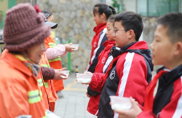 學生志愿者為社區清潔工送元宵節湯圓。九龍坡區火炬小學供圖