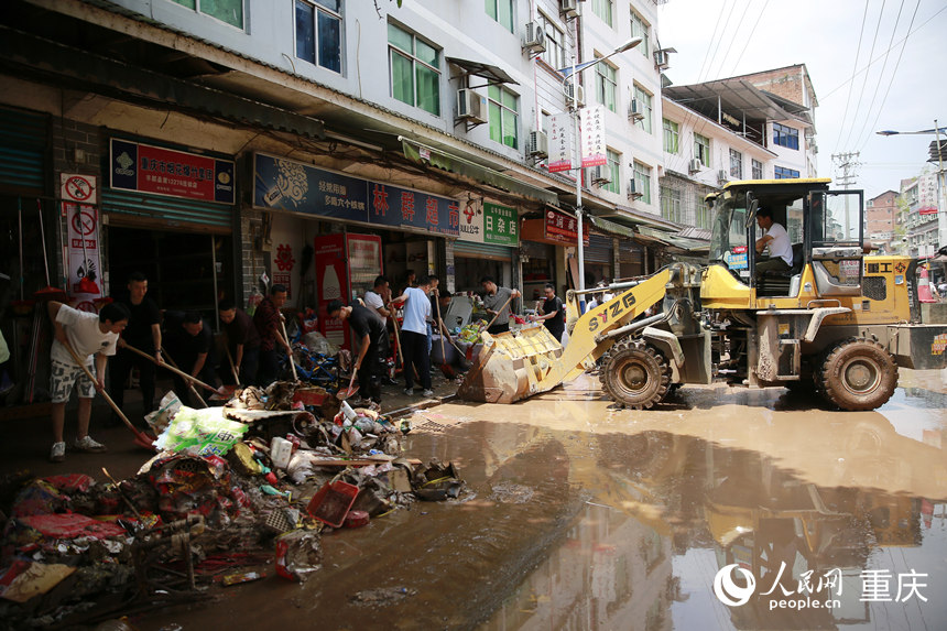 7月12日，志愿者和群眾合力清理仁沙鎮場鎮的淤泥和雜物。人民網記者 劉政寧攝