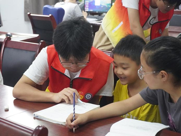 志愿者輔導孩子完成作業。重慶財經學院供圖