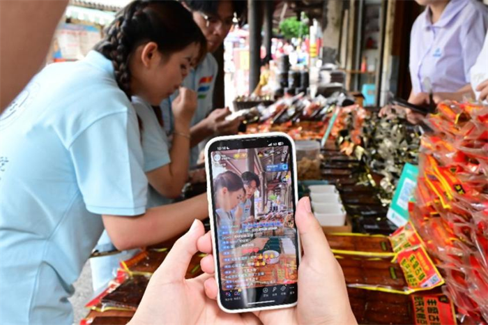 團隊成員在“彭氏火烤豆干”門店前直播展示 通訊員 王青青 供圖