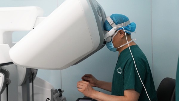 譚群友頭戴空間計算裝備，操作機器人進行手術。重慶醫科大學附屬大學城醫院供圖