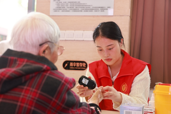 義診中，志愿者為老年人做血糖檢測。曾英豪攝