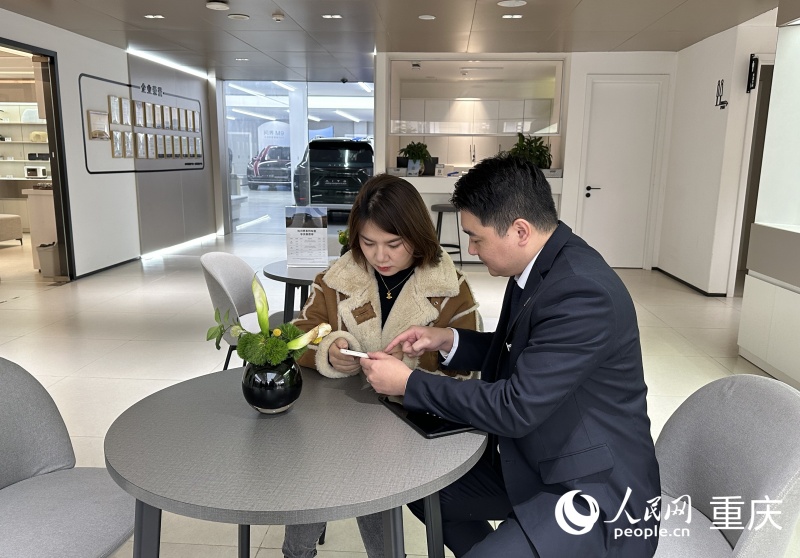 王女士在工作人員的指引下用手機辦理新車上牌業務。人民網記者 劉政寧攝