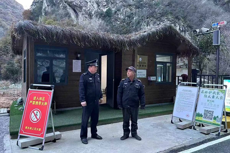 溫軍文（左）在和秦嶺聯防的民間工作人員交談。李凱攝