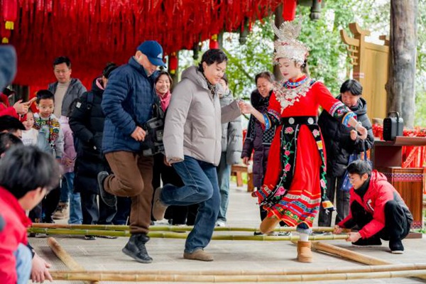 游客與嬌阿依歡跳竹竿舞。景區供圖
