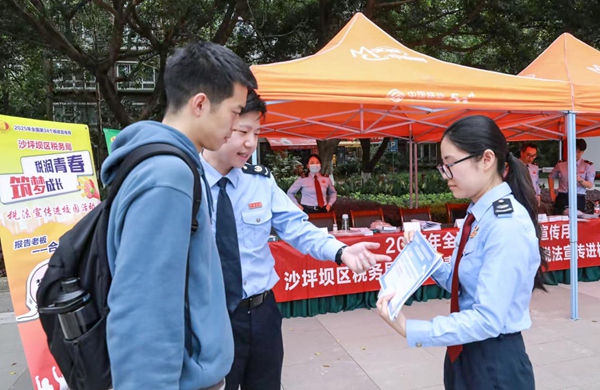 沙坪壩區稅務人員在四川外國語大學設置宣傳點，向往來學生發放宣傳冊，邀請其參與合規經營情景模擬，樹立合規經營意識。郭亞玲 攝