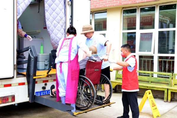 志愿者扶老人進入助浴車。楊晨攝