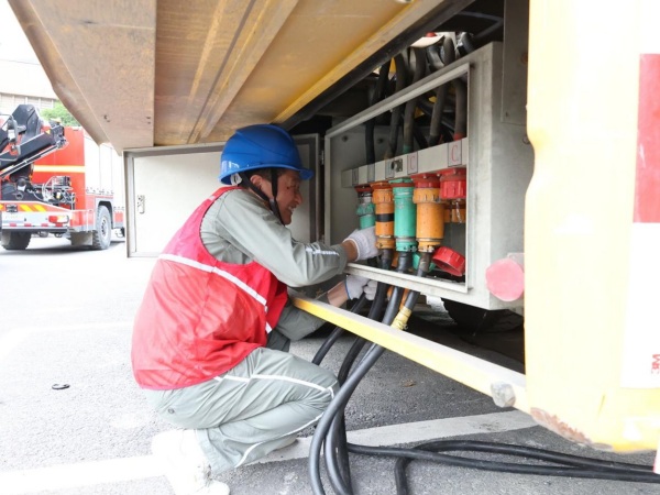 國家電網重慶電力（城口綜合）紅巖共產黨員服務隊隊員陳煉將連接有考點線路的電纜接入中壓電源車。國網城口供電公司供圖