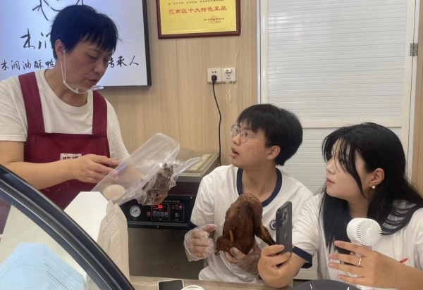 店內負責人向直播間觀眾展示改良包裝。重慶財經學院供圖