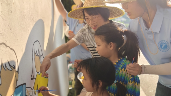 實踐團師生指導小朋友參與繪制法治墻。重慶理工大學供圖