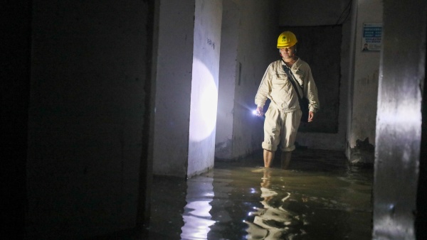 國網重慶市南供電公司員工在巴南區小灣家園涉水巡視配電設施。龔超攝