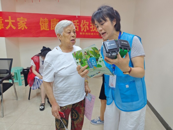 工作人員通過垃圾分類彩頁、模型等向老年人講解垃圾分類知識。呂麗珊攝