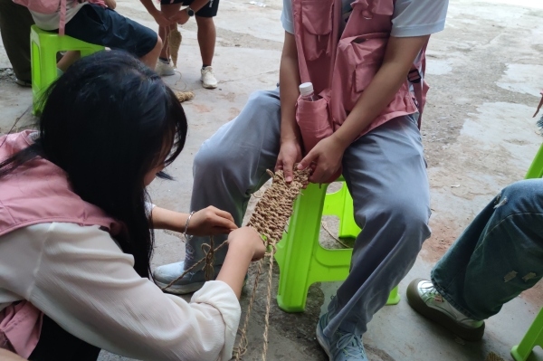團隊成員體驗編草鞋。重慶移通學院供圖