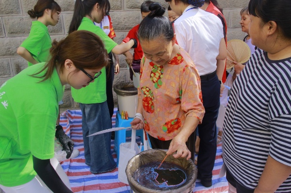 踐行團成員引導居民體驗非遺活動。重慶電力高等?？茖W校供圖