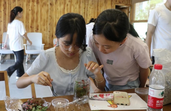 服務團成員引導小朋友親手設計生態瓶布局。重慶師范大學供圖