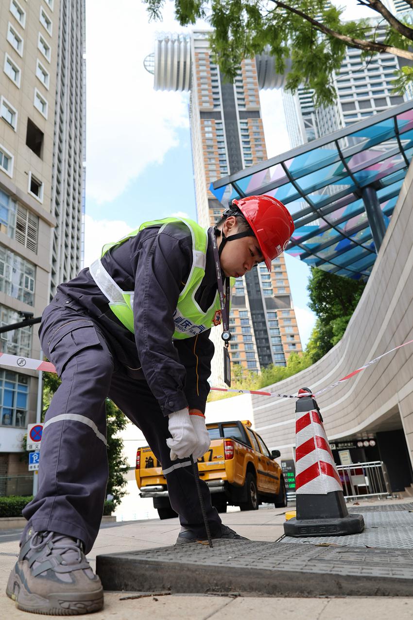渝中區來福士廣場附近，“紅巖燃小兵”使用專用工具打開閥井蓋，準備進行燃氣濃度檢測。重慶燃氣集團供圖
